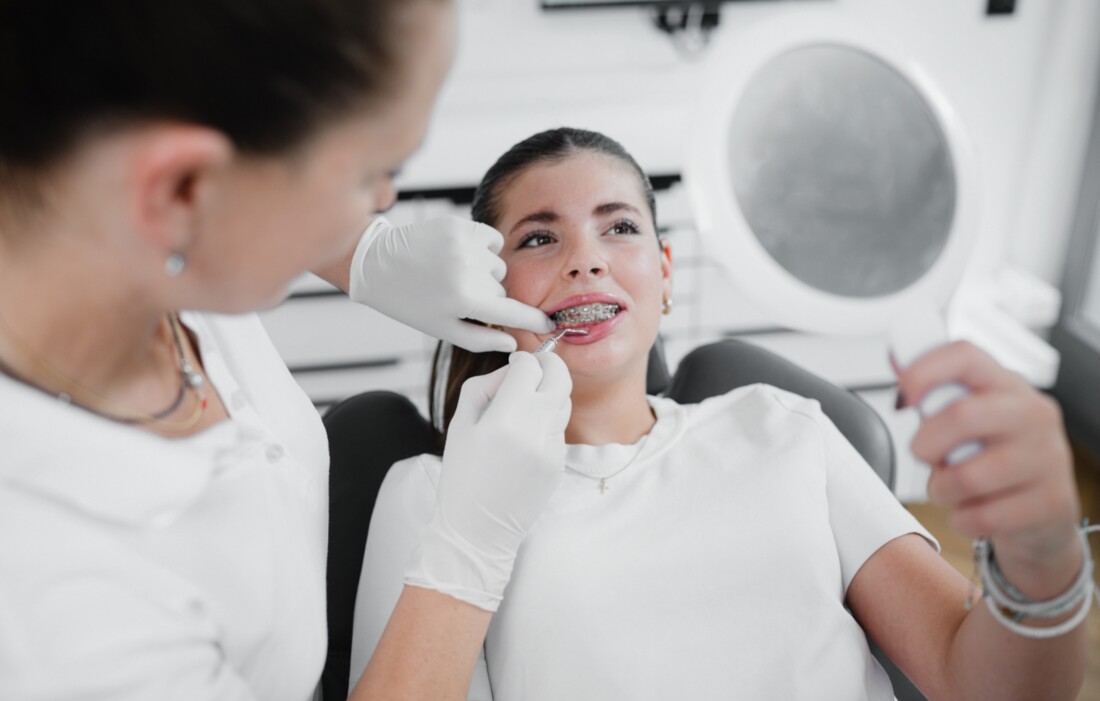 Patientin mit Zahnspange sieht sich Ergebnis im Spiegel an